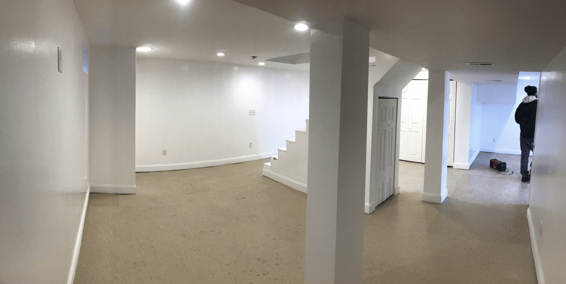 Finished basement renovation with white walls and recessed lighting